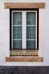 Fototapeta na wymiar Restored traditional old window in Portuguese neighborhood with white and red frame and carved metal guard