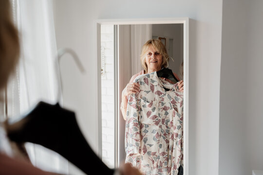 Senior woman trying on clothes at home looking at mirror