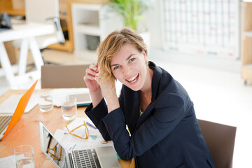 Obraz premium Portrait of woman sitting at desk with laptop in office