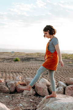 Girl walking on rocks with dirt and sky facing sideways