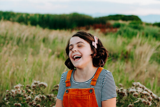 Girl in gold and stipes laughing with eyes closed.