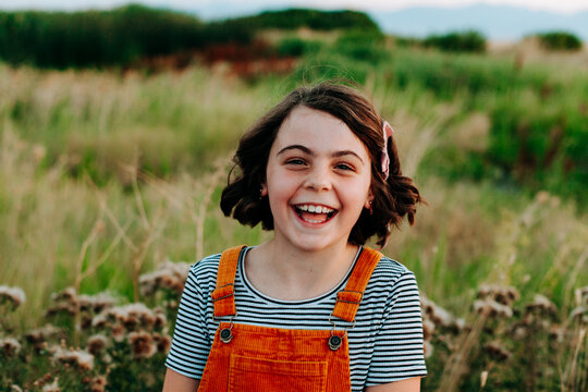 Girl in gold and stipes laughing and looking at camera.