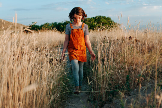 Girl walking through field of weeds on a dirt path