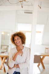 Portrait of woman leaning on column in office and smiling