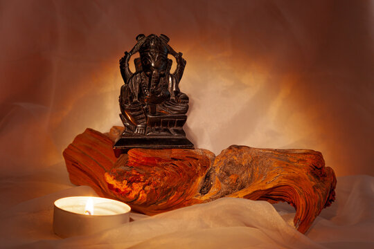 The son of Shiva, the god Ganesha, is riding on a tree in the light of a candle
