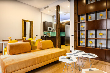 Living room and kitchen decorated in ocher and wood tones with yellow flowers and full-length gold...