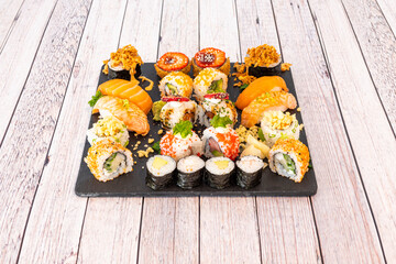 Assorted sushi tray with nori seaweed maki, uramaki california roll with masago roe, raw salmon nigiri, flambé salmon, crispy onion, cream cheese and horseradish, strawberry slices and ripe avocado