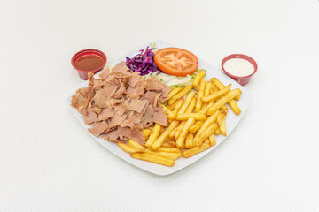 Menu lamb kebab plate with fried potatoes, chopped meat, purple cabbage, iceberg lettuce and tomato slices, yogurt and tomato sauce