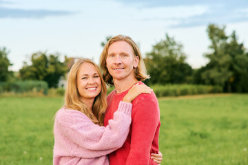 Outdoor portrait of happy young couple enjoying nice day in the nature, wearing pullovers