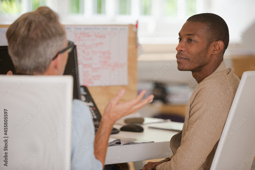 Wall mural Men sitting at desk in office and talking