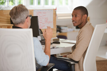 Men sitting at desk in office and talking