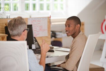 Men sitting at desk in office and talking