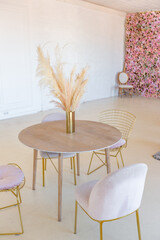delicate and cozy light interior of the living room with modern stylish furniture of pastel pink color and white walls with stucco moldings in daylight