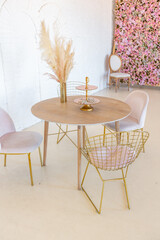 delicate and cozy light interior of the living room with modern stylish furniture of pastel pink color and white walls with stucco moldings in daylight