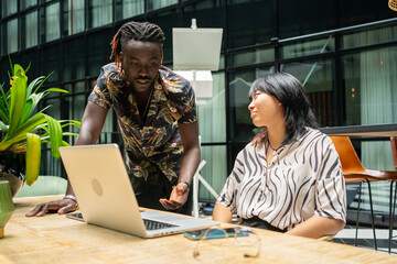 Black Man Explaining A Project To His Asian Colleague.