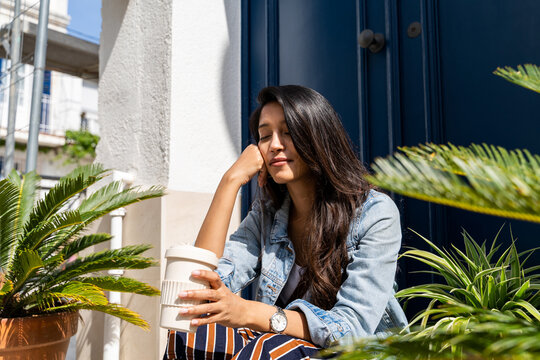 Pensive young woman meditating in doorway with closed eyes
