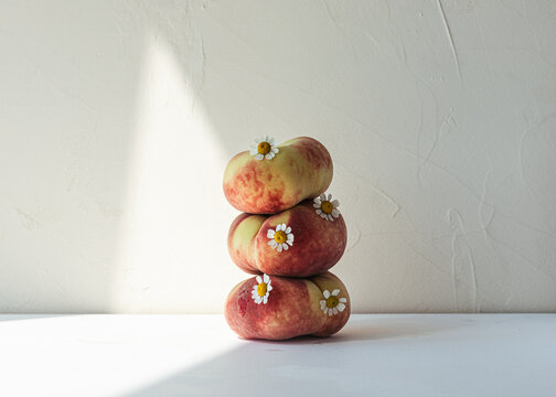 Quirky still life of stacked peaches and flowers