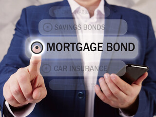  MORTGAGE BOND inscription on the screen. Close up Businessman hands holding black smart phone. A mortgage bond is a bond in which holders have a claim on the real estate assets put up