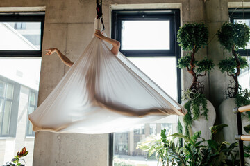 Unrecognizable woman stretching in silks