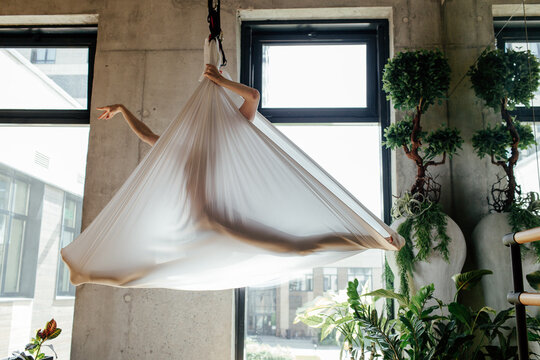 Unrecognizable woman stretching in silks