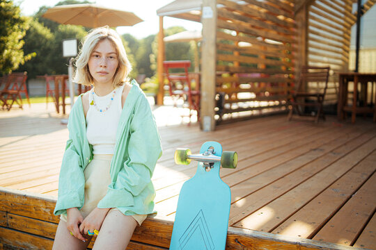 Young woman with longboard relaxing in park