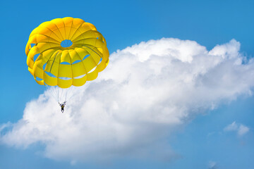 Paragliding using a parachute on background of blue cloudy sky.