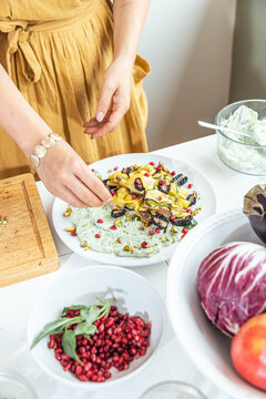 Young woman plating salad on dining table