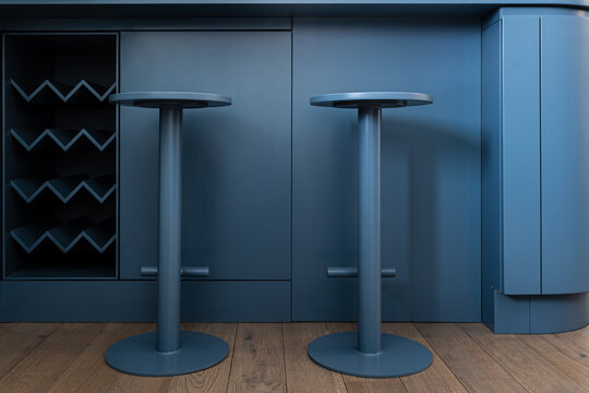 Two blue stools next to a empty wine shelf