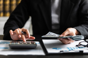 close up view of businesswomen or accountant counting dollar banknote with using calculator to...
