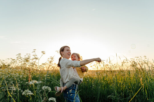 Mother and daughter blowing bubbles in meadow
