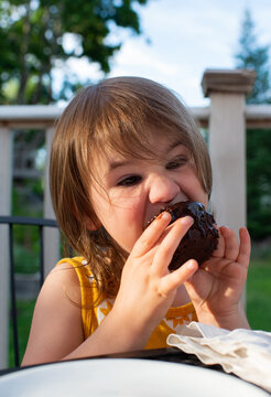 3 Year old Girl Takes Big Bite of Chocolate Cupcake