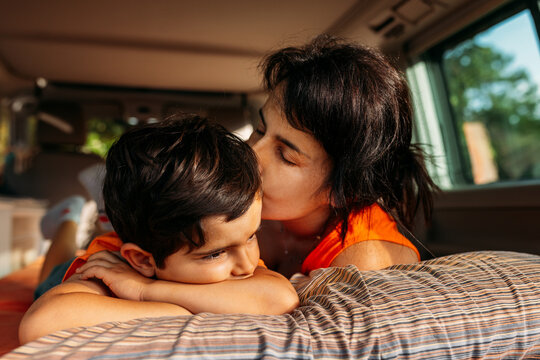 Mother kissing sleeping kid in camper van
