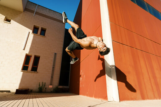 Agile sportsman doing back jump trick on street
