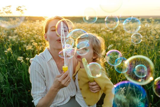 Mother and daughter playing with soap bubbles 