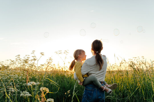 Unrecognizable mother and daughter blowing bubbles 