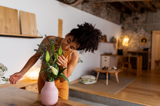 Woman Smelling Natural Flowers At Home Vase