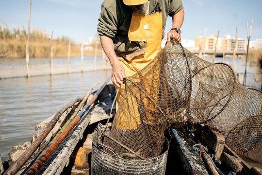 Fisherman putting the fish he caught in a bucket in his boat