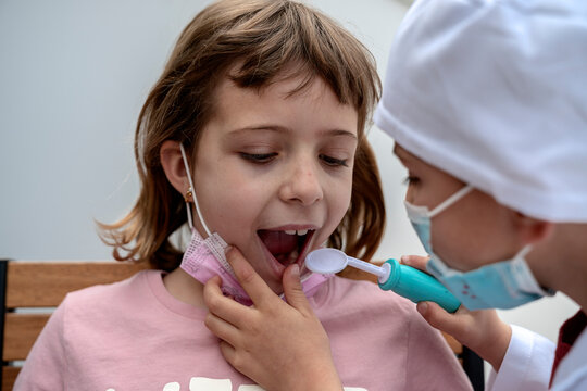 Little brother playing doctor checking teeths of his patient sister