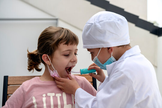 Front view of little brother playing doctor checking teeths of his patient sister