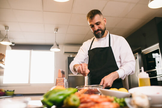 Bearded chef preparing sauce in kitchen 