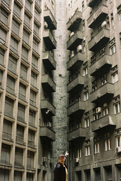 A man in front of the brutalist style buildings.
