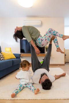 Couple with little kid practicing acroyoga at home