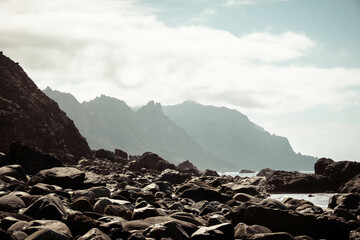 Playa de rocas con montañas y nubes de fondo. Paisaje de Tenerife