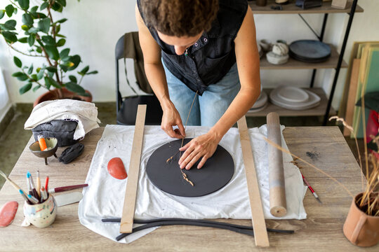 Handmade pottery workflow. Woman making ceramic plate. 