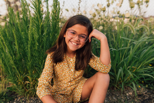 Girl sitting in a patch of wild flowers. 