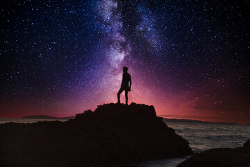 Night stars over Man’s reflection silhouette at the ocean water