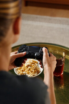 Crop female playing videogame near food