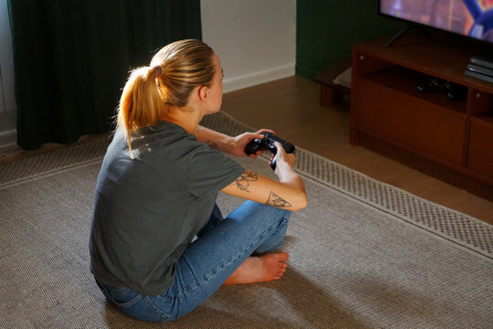 Young woman playing videogame on floor
