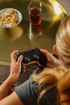 Unrecognizable female playing videogame over metal table