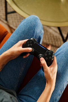 Anonymous gamer sitting on sofa near table